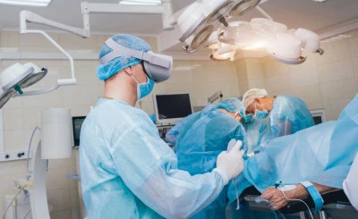 Doctor in a surgical room with virtual reality glasses on the background of the real operation.